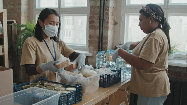 Slowmo shot of group of female volunteers preparing food in tins, water and other eatables for charity
