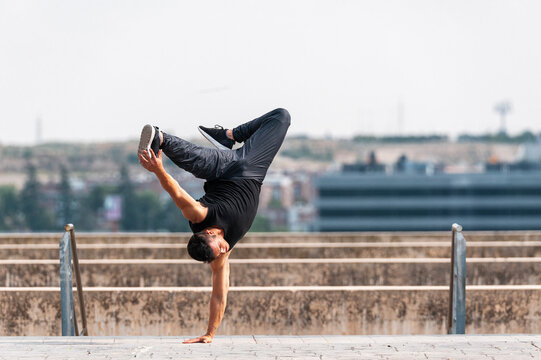 Hip-hop dancer performing a hand stand in urban scenery