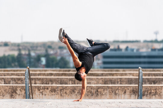 Break dancer performing a hand stand in park