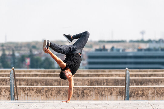 Break dancer performing athletic hand stand in park