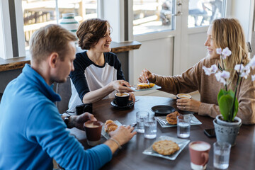Happy friends having breakfast in cafe