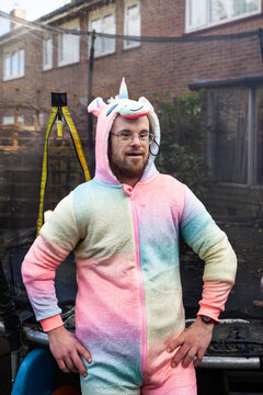 Man with down syndrome poses in a unicorn onesie.