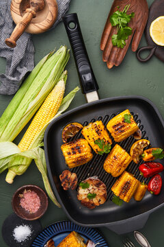 Tasty grilled corn in frying pan on table