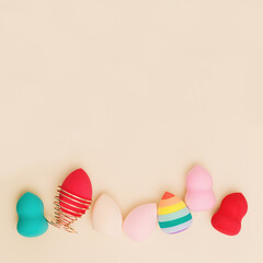 Colorful cosmetic beauty sponges close up different form on beige background with copy space. Top view, flat lay.