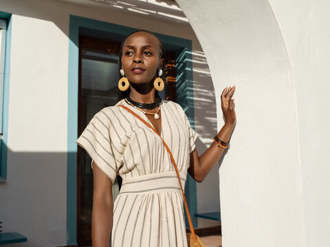 Dreamy black woman standing outside house