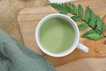 Top view of cup of green tea latte on wooden board
