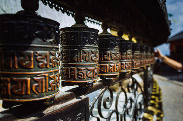 Closeup of Buddhist prayer wheels with hand in the background