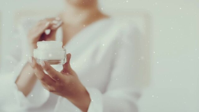 Skincare for winter season, woman holding face cream jar, falling snow and Christmas glitter. High quality FullHD footage