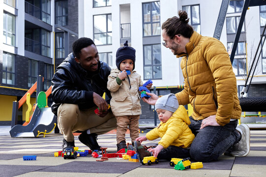 Father Proposing Toys To Child On Play Area 