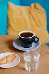  coffee in a beautiful cup, stylish restaurant or coffee shop, cappuccino or Americano for breakfast, meeting of friends or colleagues, orange pillows. a woman's hand holding a cup of black coffee