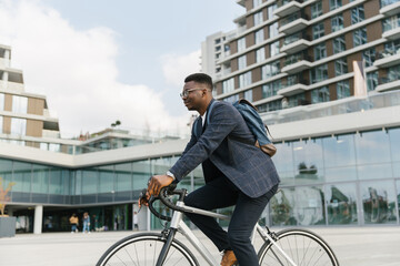 Young african american businessman riding a bicycle to work in the urban city zone 