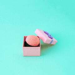 Brain as a surprise gift in a pink box. Minimal funny composition on blue backgrounds.
