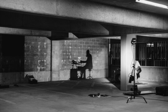 A drummers shadow is projected on the wall of a parking garage
