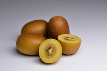 Whole and cut golden kiwifruit, kiwi (Actinidia chinensis) on grey background. Yellow kiwi fruit isolated. Gold kiwi fruit with sliced. 