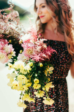 Woman in dress smiles at bouquet of flowers