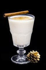 glass of hot eggnog, Christmas drink, made with eggs, cinnamon, almonds and rum liqueur. Isolated black background and copy space.