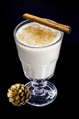 glass of hot eggnog, Christmas drink, made with eggs, cinnamon, almonds and rum liqueur. Isolated black background and copy space.