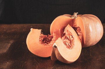 Whole fresh orange big pumpkin and slice of pumpkin on black background, closeup. Organic...