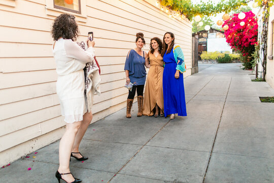 Mature woman taking photo of friends on smartphone