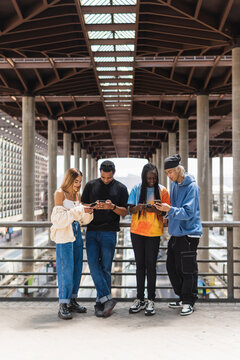 Group pf diverse friends using smartphones in city