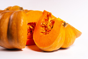 Whole fresh orange big pumpkin and slice of pumpkin on white background, closeup. Organic agricultural product, ingredients for cooking, healthy food vegan.