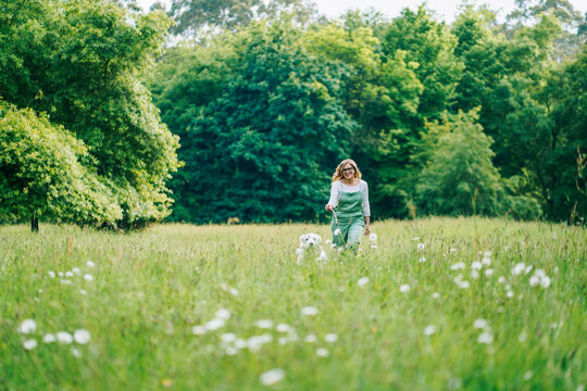 A woman walks with her dog through a park

 - Powered by Adobe