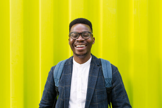 Cheerful outdoor portrait of a young black male against yellow background 