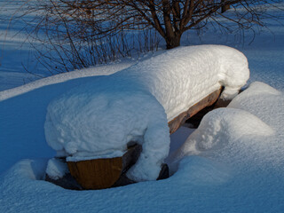 Snow-covered bench lit by sunlight