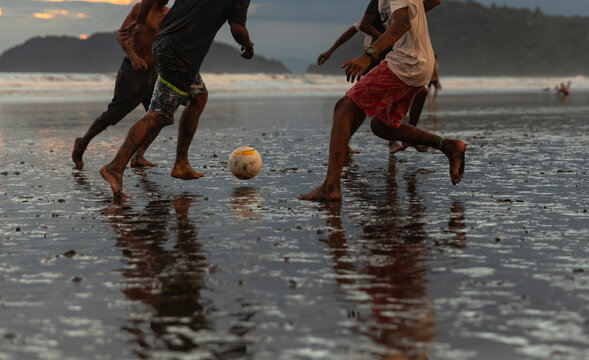 Man Runs After Soccer ball on beach during game 