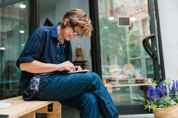 Smiling ceramist with a telephone outside the workshop