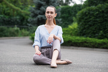 Portrait of a beautiful and attractive Caucasian girl sitting on the road in the park.