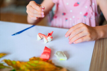 Little girl sculpts a toy from plasticine at home. Concept DIY