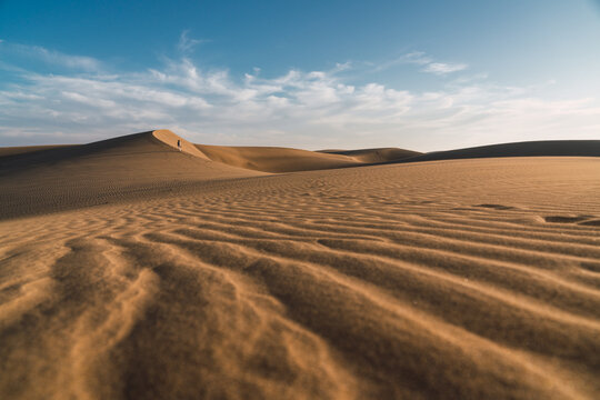 Back view woman walking on sand land and blue sky at sunset