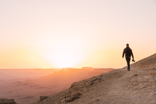 Man holding a camera walking during susnet.