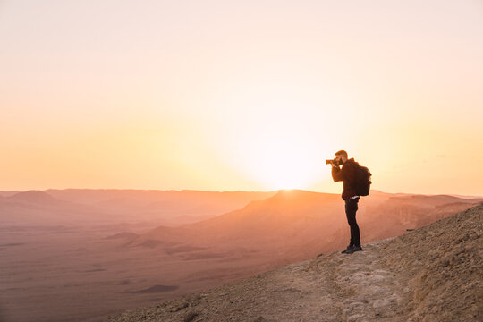 Man standing on a cliff during sunset.