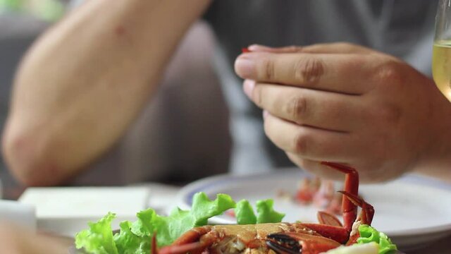 Man eating a red crab with his hands