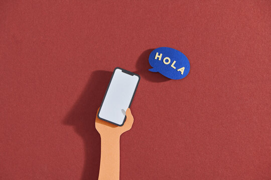 Mobile phone in hand and speech bubble, text hola