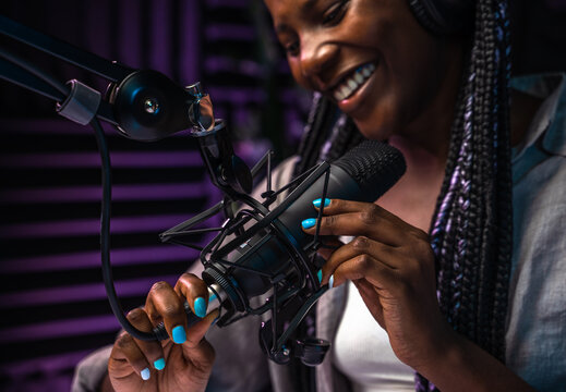 Smiling podcast host fixing microphone