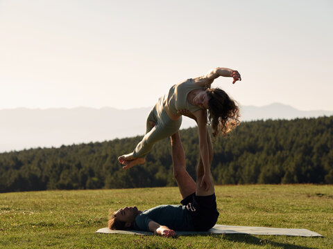 Calm couple performing side pose of acro yoga