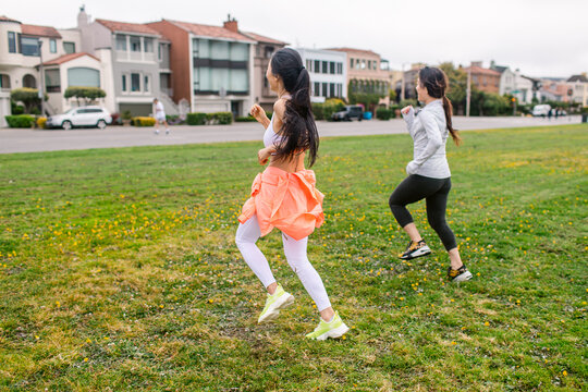 Unrecognizable sportswomen jogging on grass