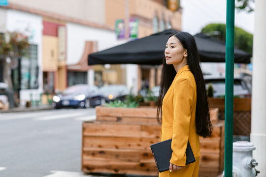 Long hair woman on professional suit standing on street
