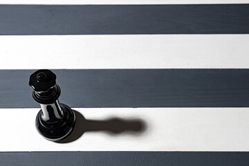 a shadow cast by a black chess piece on a white stripe. non-standard field for the game. striped...