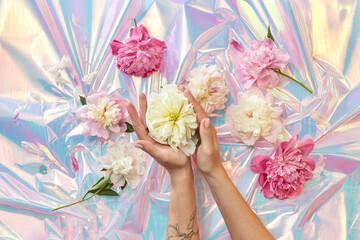 Woman holding peonies at holographic foil