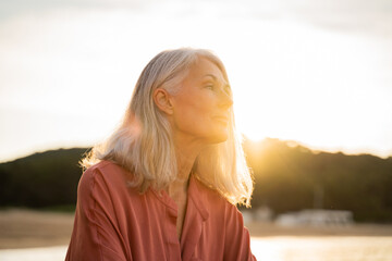 Obraz premium Beautiful pensive mature woman relaxing at beach
