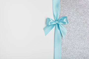 Shiny blue gift ribbon bow on white and silver background