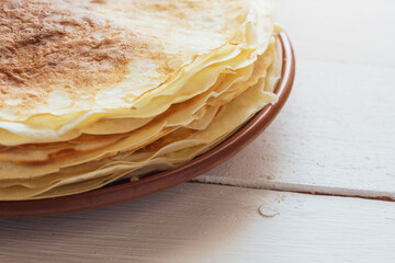 Crepes, thin pancakes on a plate on a white wooden table