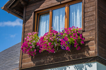 Fototapeta na wymiar The wooden mezzanine of an old farm mountain house with colorfull flowers in Austria