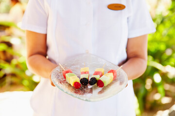 Resort staff service person holding fruit skewer at spa