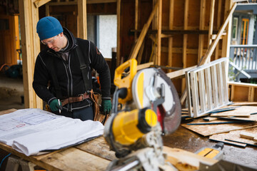 Carpenter reading construction plans on the job site in winter