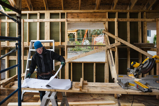 Carpenter reading construction plans on the job site in winter